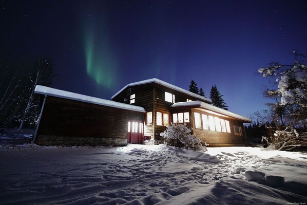 Marvel at the magical Northern Lights dancing above this cozy Alaskan cabin, a perfect blend of serenity and natural wonder