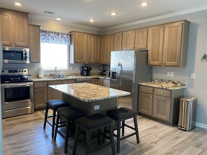 Kitchen with island seating and appliances including dual coffee maker.
