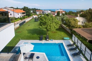 Balcony view at the private terrace of Medulin luxury villa with pool and deckchairs with sunshade for vacation