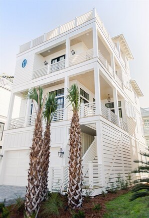A coastal dream home with a stunning exterior and lush landscaping.
