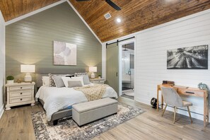 The spacious primary bedroom features a comfortable king-sized bed and a work desk, overlooking the luxurious ensuite bathroom.