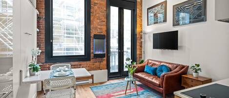 This vibrant and modern studio boasts an open-concept design with beautiful exposed brick, high ceilings, and abundant natural light from the building's original architecture.
