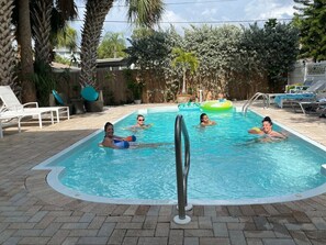 Expansive pool area featuring comfortable beach beds and inflatable ring floaters.