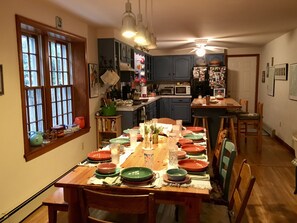 Large open kitchen with counter and stools, large dining table.