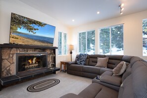 This large living room offers plenty of space to relax, featuring a cozy wood-burning fireplace and a huge flat-screen TV, perfect for family movie nights