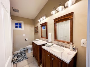 Bathroom with tile shower, double vanity, and laundry