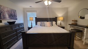 Spacious master bedroom with king size bed, dresser, and nice desk or work area