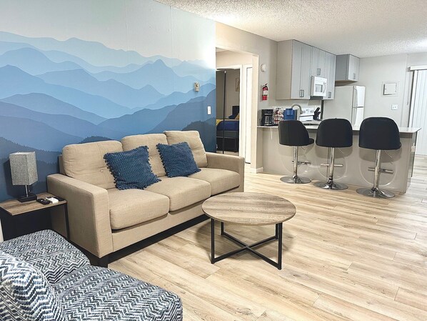 Spacious Living Room with Cozy Fireplace & Mountain Views
Unwind in this thoughtfully designed living room, featuring a comfortable 3-seater sofa with cozy throws, perfect for relaxation.