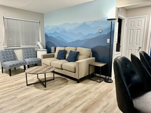 The round center table and accent chairs create a stylish yet comfortable space, perfect for unwinding. With a huge window letting in natural light and a beautifully painted wall, this space offers both tranquility and charm.