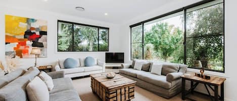 A sunken living space off the dining area provides a comfy sofa and armchairs where guests can settle in with a movie. Colourful local artwork is featured throughout the home. 
