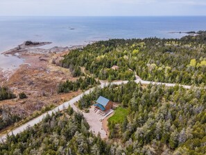 An aerial view captures the cabin's secluded location amidst lush greenery, offering breathtaking vistas of the surrounding landscape and waters.