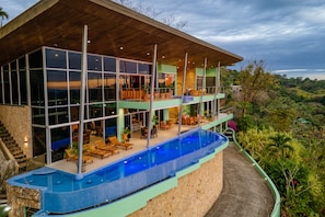 The villa features floor to ceiling glass windows and doors, terraces and pool.