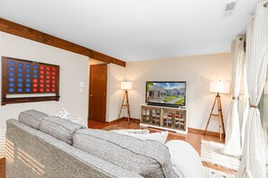 Lower level living room with full-sized sofa bed, 58-inch Roku HDTV, deck access