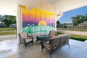 "Outdoor Oasis: Covered Space with Inviting Seating, Ample Lighting, and Beautiful Mural View - Perfect for Spending Time Outdoors and Enjoying the Scenery in Comfort and Style"