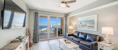 The living area with large flat screen television, overlooking the sugar white sands and the Gulf of Mexico, with doors leading to the unit's private balcony.