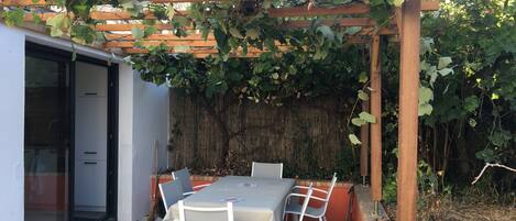 terrasse ombragée par une pergola recouverte de feuilles de vigne