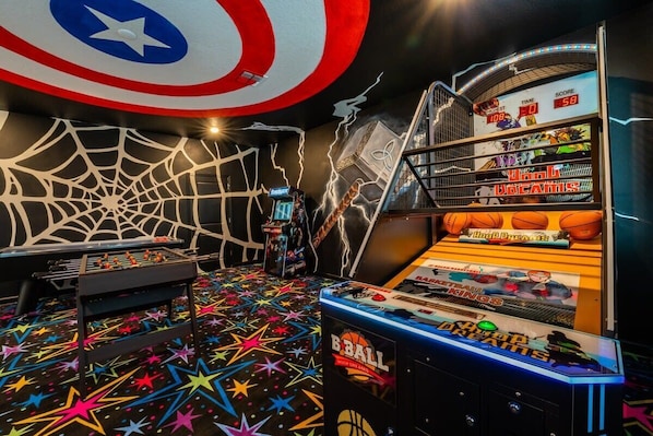 Unleash your inner hero in this vibrant game room with arcade games, foosball, and superhero decor!