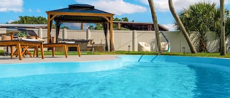 Bask in the sun and unwind in our private backyard, complete with a sparkling pool, lounge chairs, and a cozy gazebo.