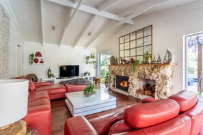 Unwind by the rustic stone fireplace on cool evenings, where the vibrant garden just beyond the window enhances the warm, welcoming atmosphere of the lounge.
