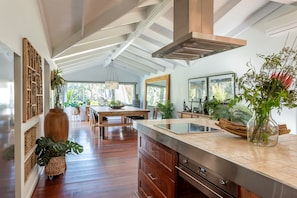 Cook up a feast in the expansive chef’s kitchen, then gather around the timber dining table as light filters through the surrounding greenery—an inviting space to share meals and stories.