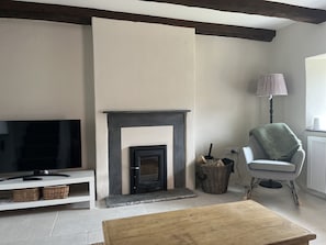 The sitting room with wood-burning stove and original  exposed beams