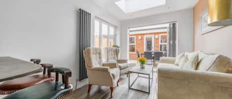 Bright living room with sofa bed, table, smart TV, and 2 arm chairs. 