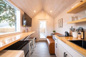 The advantage of a tiny house is that literally everything is right there — a 55” tv, pullout couch, kitchen sink and stove, fridge, and washer dryer combo with a view of our beautiful back yard.