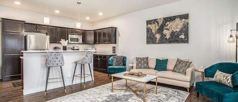 Opulent 1920's Gatsby-themed living room with black and gold accents throughout, featuring a bar seating with two chairs and a world map on the wall.