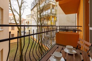 A charming balcony with a small table, two chairs, and a view of the surrounding greenery.
