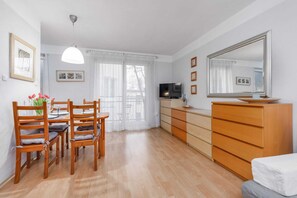 A dining area with a wooden table, chairs, and a dresser, bathed in natural light.
