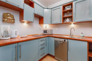 A compact and functional kitchen with wooden countertops, blue cabinets, and modern appliances.
