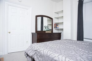 Bedroom with solid cherry queen size bed, 7 drawer dresser, and mirror.