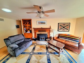 Living room with couch, love seat, two arm chairs, big screen TV, fireplace. 