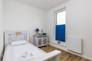 The cosy bedroom with functional single bed, wardrobe, and cabinet.
