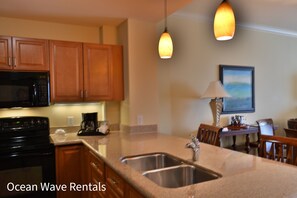 Modern kitchen with granite, dual sink, wood cabinets, and pendant lights.