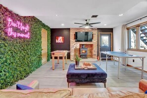 Game room, green wall+LED sign, ping pong, foosball, 55 inch TV, fireplace, bar.