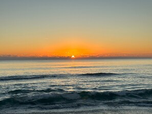 Standing on Cocoa Beach, the soft sand beneath your feet, as the sun rises over the horizon, painting the sky with hues of orange and pink. A moment of pure tranquility.