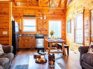 In this cabin, unwind in the cozy open space where kitchen, dining, and living flow seamlessly.