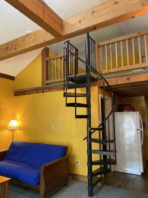 The loft above the living area is accessed by a spiral staircase. 