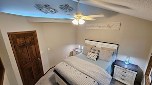 Master bedroom with vaulted ceiling, accent lighting, and views of the lake