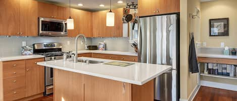 Fully outfitted kitchen with quartz counters and SS appliances.