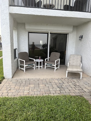 Patio with comfortable cushioned chairs, just feet from pool and beach access