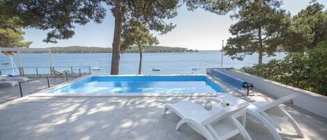 View of the sea from the spacious terrace with pool surrounded by sun loungers in front of the luxury villa Kallithea for vacation and rental