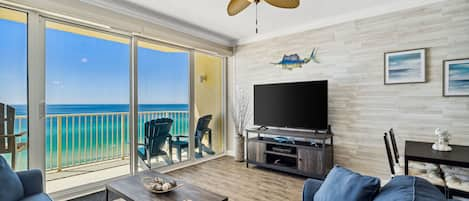 Living room offers ample, comfortable seating with flat screen television, gulf views, and a door leading to the unit's private balcony.