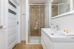 The bathroom's contemporary design includes fresh towels and a hairdryer. 