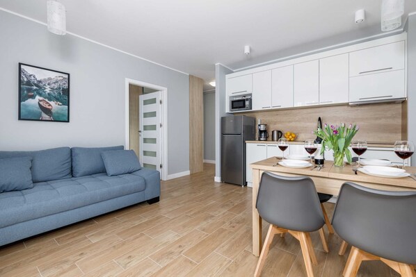 The living area features a sleek dining table and a flat-screen television.