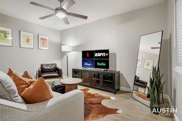 Living room with sleeper sofa, smart tv, and full length mirror