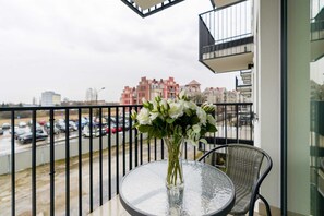 A balcony view with a small table, chairs, and an urban skyline in the background, perfect for outdoor relaxation.
