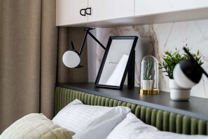 A close-up of a bedside table with decor accents like a small plant and framed art.
