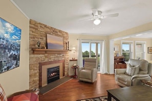 Nestled in nature's embrace, our living room invites you to cherish cozy moments by the fireplace. #ComfortMeetsNature